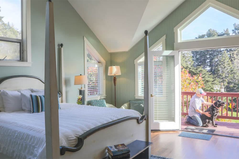Cozy bedroom with a four-poster bed, overlooking a patio with a man and dog.